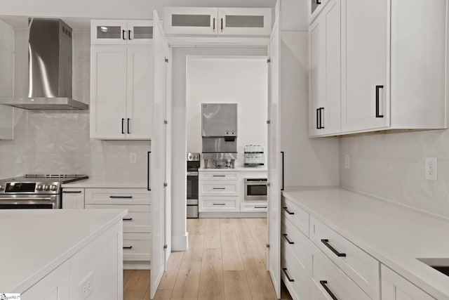 421 Lynn Rd, Taylors, SC 29687 - kitchen featuring wall chimney range hood, appliances with stainless steel finishes, white cabinetry, light countertops, and light wood finished floors
