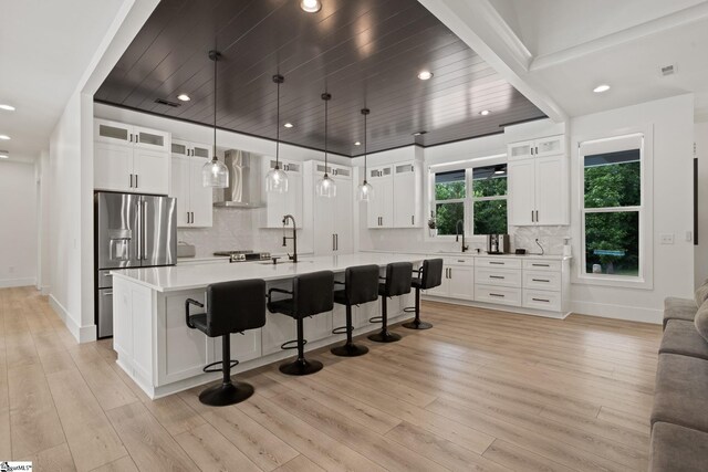 421 Lynn Rd, Taylors, SC 29687 - kitchen featuring stainless steel fridge with ice dispenser, wall chimney range hood, light countertops, a kitchen breakfast bar, and decorative backsplash