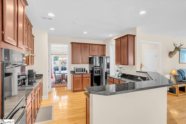 109 Amberleaf Way, Simpsonville, SC 29681 - kitchen featuring black appliances, light wood-type flooring, a peninsula, brown cabinetry, and dark stone counters