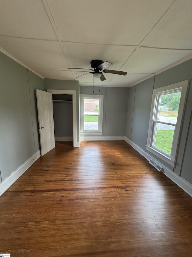 23 N Greenwood Avenue Extension, Ware Shoals, SC 29692 - unfurnished bedroom with ornamental molding, multiple windows, dark wood-style flooring, ceiling fan, and a closet