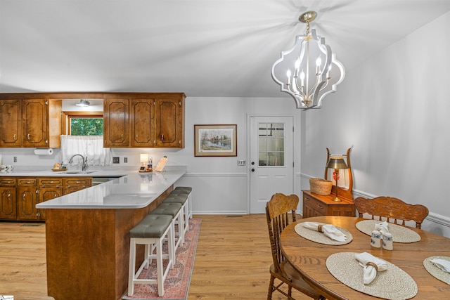 421 E Westbrooks Rd, Seneca, SC 29678 - kitchen with light wood-type flooring, a peninsula, light countertops, brown cabinetry, and a kitchen breakfast bar