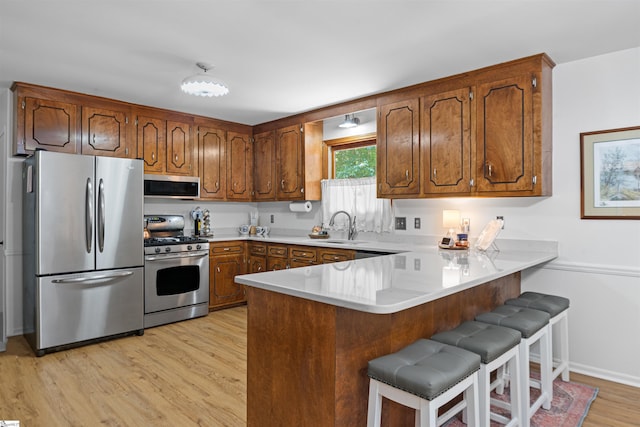421 E Westbrooks Rd, Seneca, SC 29678 - kitchen with appliances with stainless steel finishes, a peninsula, brown cabinetry, light wood finished floors, and light countertops