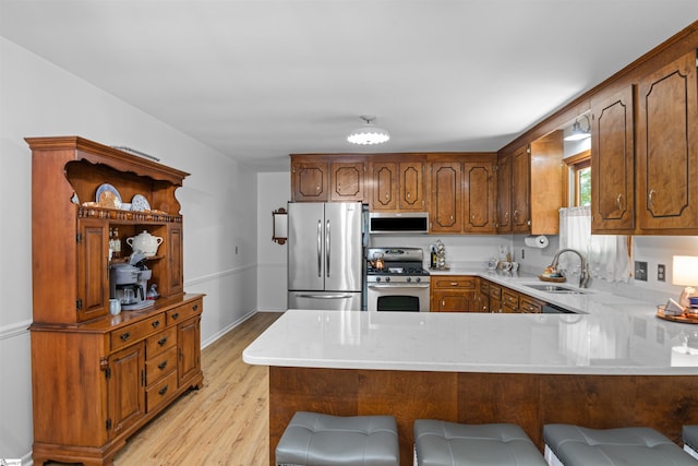 421 E Westbrooks Rd, Seneca, SC 29678 - kitchen with stainless steel appliances, light wood-style flooring, a peninsula, brown cabinets, and a kitchen breakfast bar