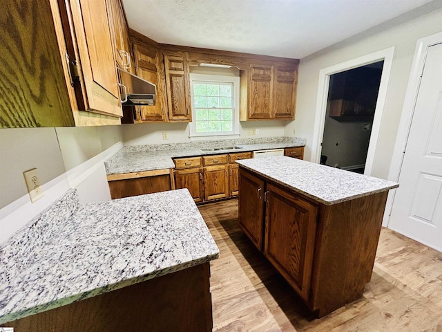 10628 Augusta Rd, Belton, SC 29627 - kitchen featuring light wood-style flooring, exhaust hood, a center island, and brown cabinetry