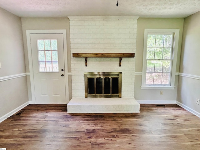 10628 Augusta Rd, Belton, SC 29627 - unfurnished living room featuring wood finished floors, a textured ceiling, and a brick fireplace