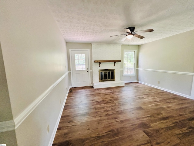 10628 Augusta Rd, Belton, SC 29627 - unfurnished living room with a textured ceiling, healthy amount of natural light, ceiling fan, dark wood-style flooring, and a brick fireplace