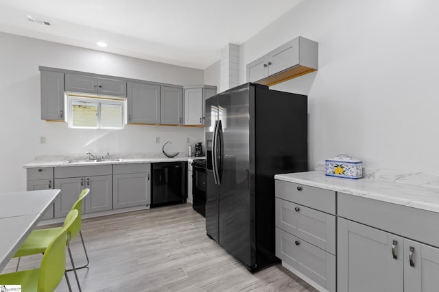 904 W Hampton St, Laurens, SC 29360 - kitchen with gray cabinetry, black appliances, light wood-style flooring, recessed lighting, and light stone countertops
