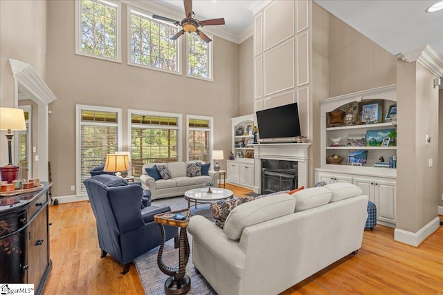 112 Griffith Hill Way, Greer, SC 29650 - living room featuring ornamental molding, a ceiling fan, a towering ceiling, a fireplace, and light wood-style flooring