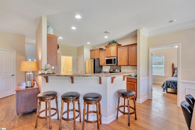 402 Birchbark Ln, Lyman, SC 29365 - kitchen featuring stainless steel appliances, a kitchen breakfast bar, light wood-style flooring, light stone countertops, and a peninsula