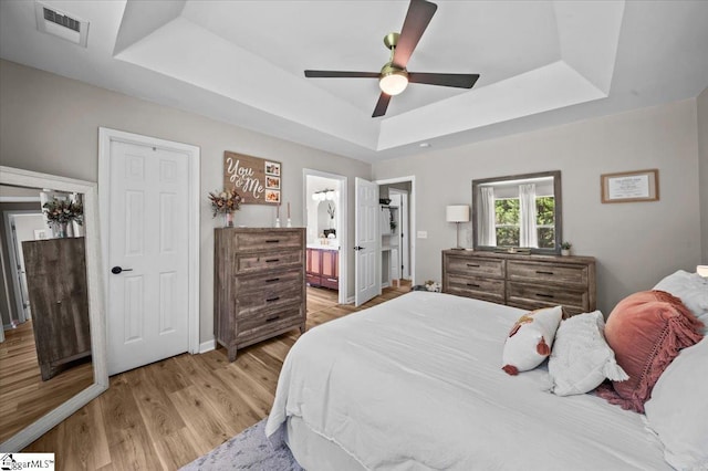 521 Omniwood Ct, Greer, SC 29651 - bedroom featuring a raised ceiling, light wood-style flooring, ensuite bathroom, and a ceiling fan