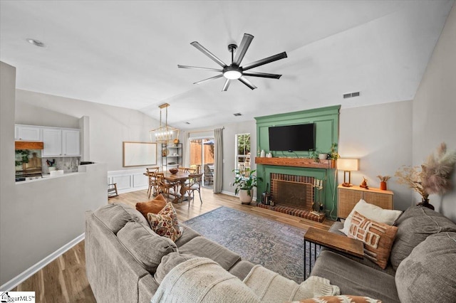 521 Omniwood Ct, Greer, SC 29651 - living area featuring light wood-type flooring, a ceiling fan, vaulted ceiling, a fireplace, and a chandelier