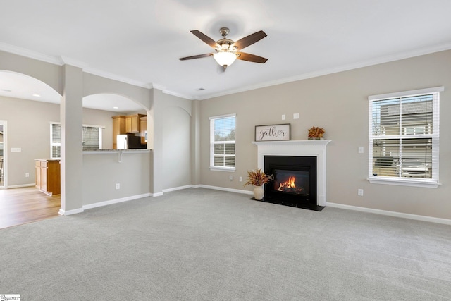 463 Lynnell Way, Moore, SC 29369 - unfurnished living room with light colored carpet, crown molding, a ceiling fan, a fireplace with flush hearth, and arched walkways