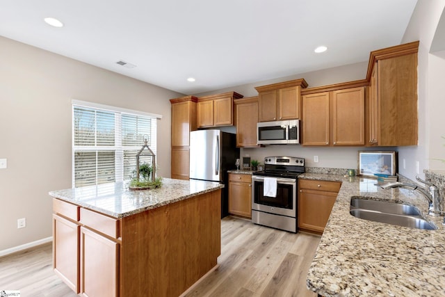 463 Lynnell Way, Moore, SC 29369 - kitchen with stainless steel appliances, light wood-style flooring, a center island, light stone countertops, and brown cabinets