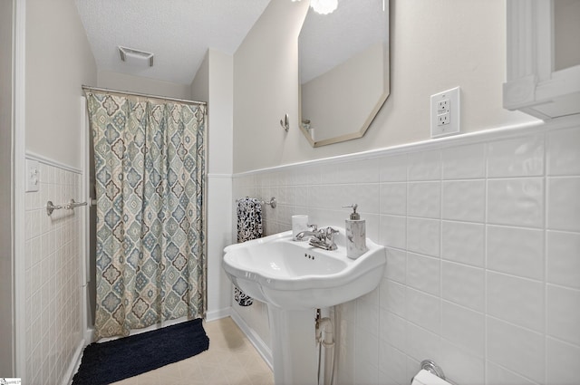 260 Riggs Dr, Clemson, SC 29631 - full bathroom with tile walls, wainscoting, a shower with shower curtain, and a textured ceiling