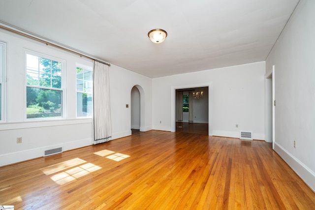 306 Mcdaniel Ave, Greenville, SC 29601 - empty room featuring arched walkways, healthy amount of natural light, light wood-type flooring, and a chandelier