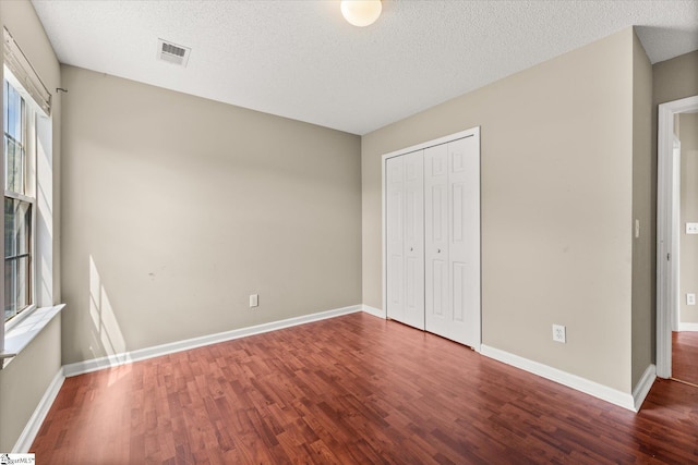 323 Waterton Way, Simpsonville, SC 29680 - unfurnished bedroom featuring wood finished floors, multiple windows, a textured ceiling, and a closet