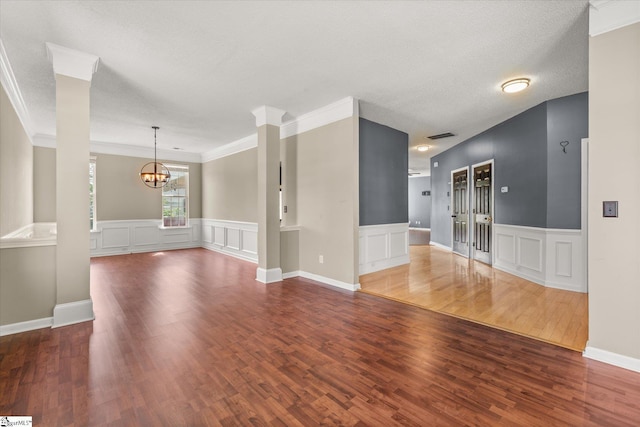 323 Waterton Way, Simpsonville, SC 29680 - unfurnished living room featuring a chandelier, a decorative wall, wood finished floors, wainscoting, and ornamental molding