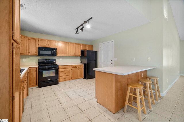 210 Admiral Ln, Greer, SC 29650 - kitchen with black appliances, a peninsula, light countertops, a breakfast bar area, and light tile patterned floors