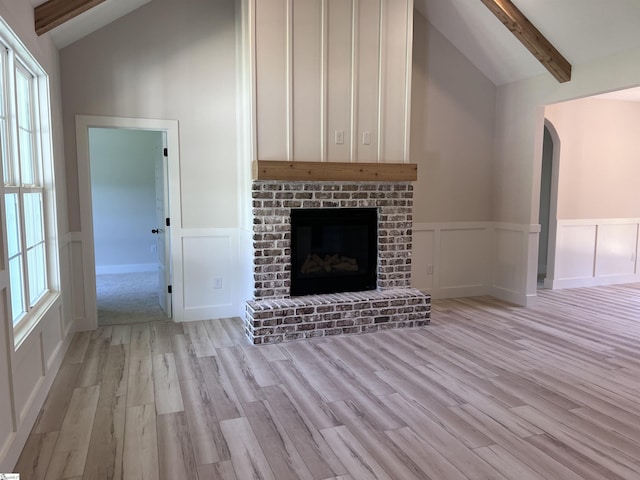 3352 Earls Bridge Rd, Easley, SC 29640 - unfurnished living room featuring light wood-style floors, arched walkways, a decorative wall, a fireplace, and wainscoting