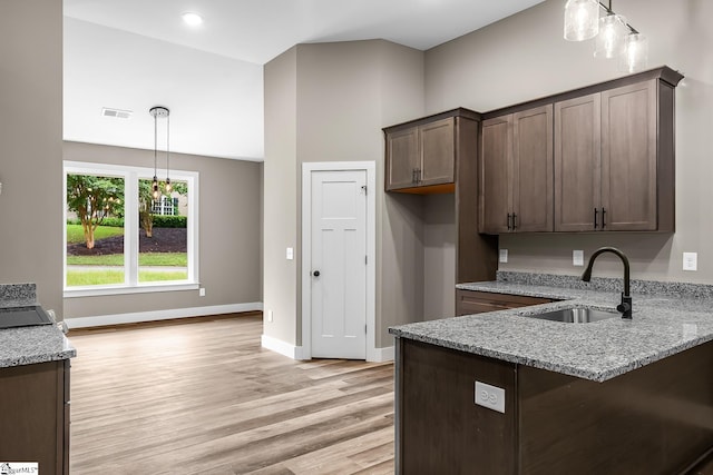 156 Grand Oak Cir, Pendleton, SC 29670 - kitchen with light stone counters, light wood finished floors, decorative light fixtures, dark brown cabinets, and a peninsula