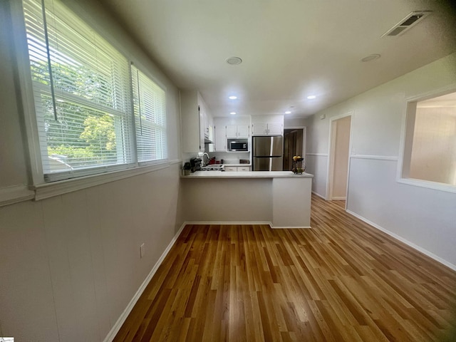 3023 Plainview Rd, Anderson, SC 29626 - kitchen with stainless steel appliances, a peninsula, wood finished floors, white cabinets, and light countertops