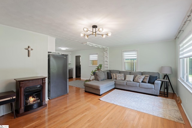 1142 Cooper Bridge Rd, Woodruff, SC 29388 - living room featuring light wood-style floors, plenty of natural light, a chandelier, and a warm lit fireplace