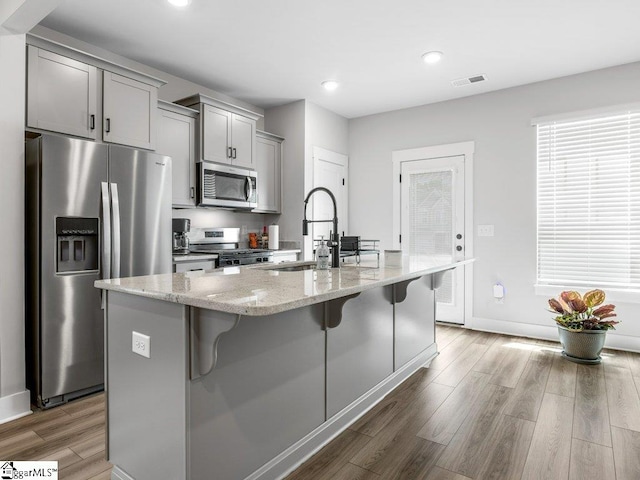 1215 Cherry Orchard Rd, Moore, SC 29369 - kitchen with appliances with stainless steel finishes, gray cabinets, a kitchen bar, light wood finished floors, and a center island with sink