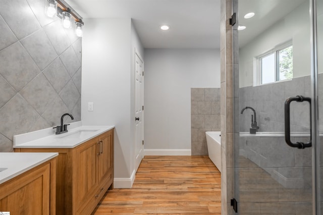 5 Mcgee St, Belton, SC 29627 - bathroom featuring two vanities, wood finished floors, a garden tub, recessed lighting, and a stall shower