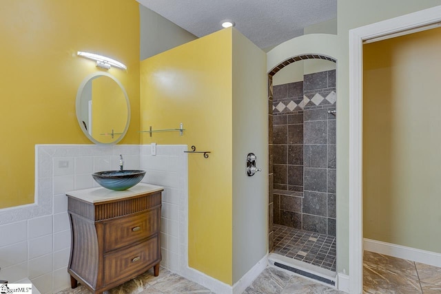 450 Johnson Ave, Anderson, SC 29621 - bathroom featuring tile walls, a tile shower, a textured ceiling, marble look tile flooring, and vanity