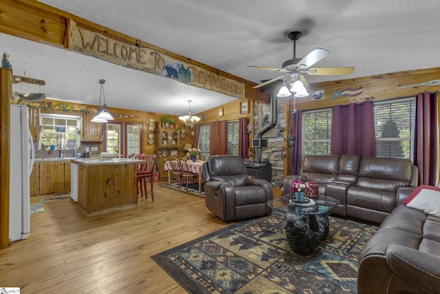 495 Pleasant Grove Rd, Pickens, SC 29671 - living room featuring a wood stove, a textured ceiling, wooden walls, a chandelier, and light wood-style flooring