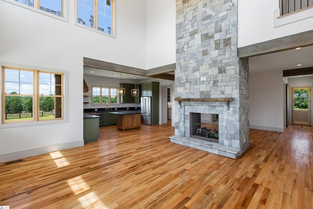 621 Bascule Ridge Ln, Campobello, SC 29322 - unfurnished living room with a towering ceiling, light wood-style floors, and a fireplace