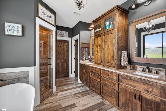 515 Herman Brooks Rd, Belton, SC 29627 - bathroom featuring a freestanding bath, double vanity, a stall shower, wood finished floors, and a chandelier