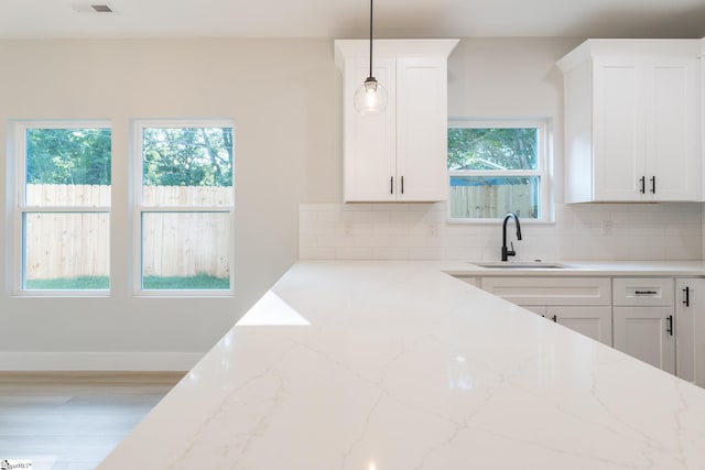 166 Dunbar St, Wellford, SC 29385 - kitchen with decorative backsplash, white cabinets, light stone counters, and hanging light fixtures