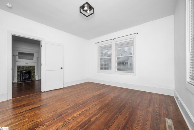 521 Anderson St, Greenville, SC 29601 - empty room with wood finished floors, a smoke detector, and a stone fireplace