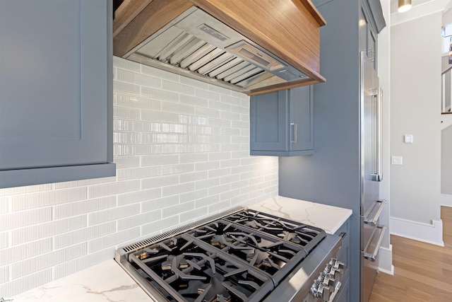 404 Odell St, Greenville, SC 29615 - kitchen featuring stainless steel range with gas cooktop, custom exhaust hood, decorative backsplash, light stone counters, and blue cabinets