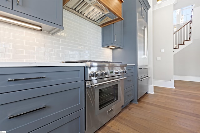 404 Odell St, Greenville, SC 29615 - kitchen featuring high end appliances, wall chimney exhaust hood, tasteful backsplash, light wood-type flooring, and light countertops