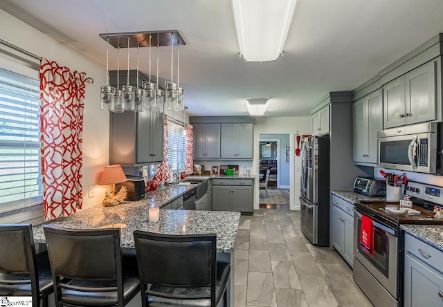 849 Harvey Rd, Greer, SC 29651 - kitchen with stainless steel appliances, stone counters, gray cabinets, a peninsula, and a breakfast bar area