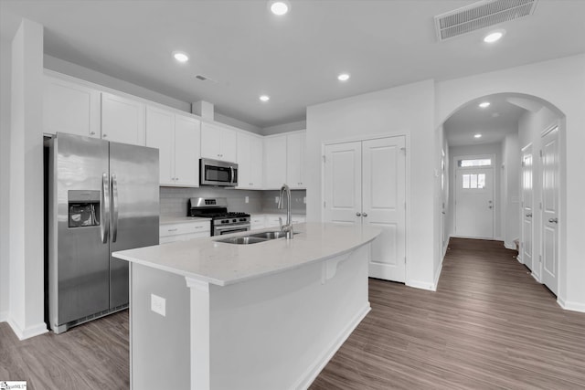 313 E Compass Way, Easley, SC 29640 - kitchen with stainless steel appliances, arched walkways, white cabinetry, wood finished floors, and an island with sink