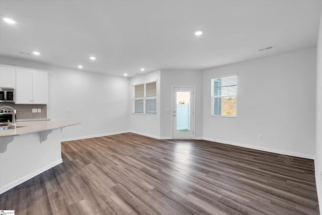 292 E Compass Way, Easley, SC 29640 - kitchen with stainless steel microwave, light countertops, a kitchen breakfast bar, tasteful backsplash, and dark wood-type flooring