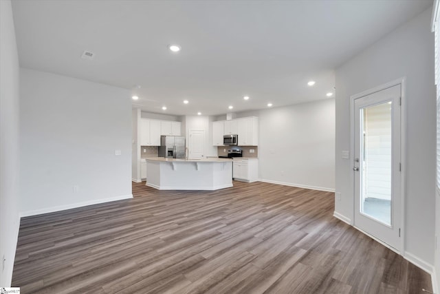 292 E Compass Way, Easley, SC 29640 - kitchen featuring appliances with stainless steel finishes, open floor plan, wood finished floors, a kitchen island with sink, and a breakfast bar area