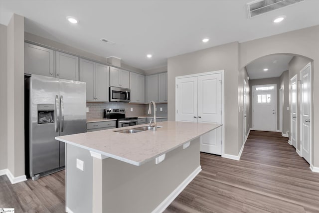 291 E Compass Way, Easley, SC 29640 - kitchen with appliances with stainless steel finishes, arched walkways, gray cabinets, light wood-style floors, and an island with sink