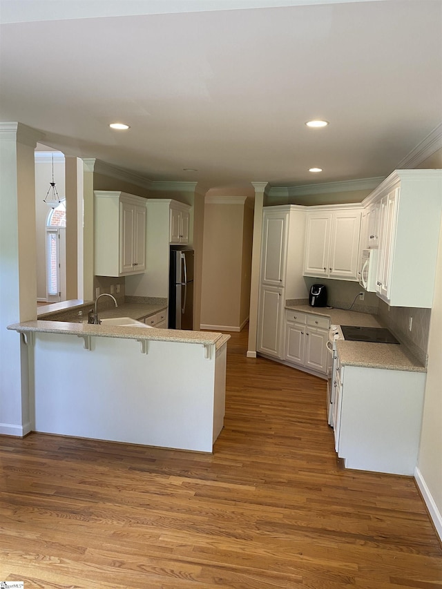 523 Meadowsweet Ln, Greenville, SC 29615 - kitchen featuring white appliances, a peninsula, ornamental molding, a breakfast bar, and light wood-style flooring