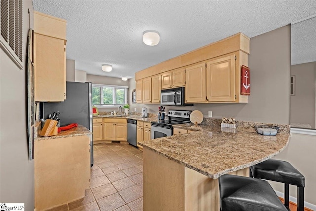701 Loran Pointe Pointe, Seneca, SC 29672 - kitchen with appliances with stainless steel finishes, light brown cabinetry, a peninsula, light stone countertops, and a textured ceiling