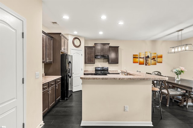 144 Caledonia Dr, Easley, SC 29642 - kitchen with black appliances, dark brown cabinetry, dark wood-style floors, a kitchen island with sink, and a breakfast bar
