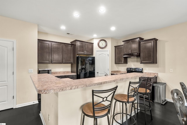 144 Caledonia Dr, Easley, SC 29642 - kitchen featuring black appliances, under cabinet range hood, dark brown cabinets, light countertops, and a kitchen bar