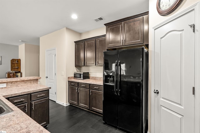 144 Caledonia Dr, Easley, SC 29642 - kitchen featuring black fridge with ice dispenser, stainless steel microwave, dark wood finished floors, dark brown cabinetry, and light countertops