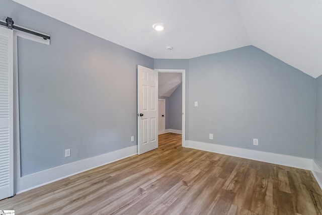 17 Allen St, Enoree, SC 29335 - unfurnished bedroom with vaulted ceiling, a barn door, and wood finished floors