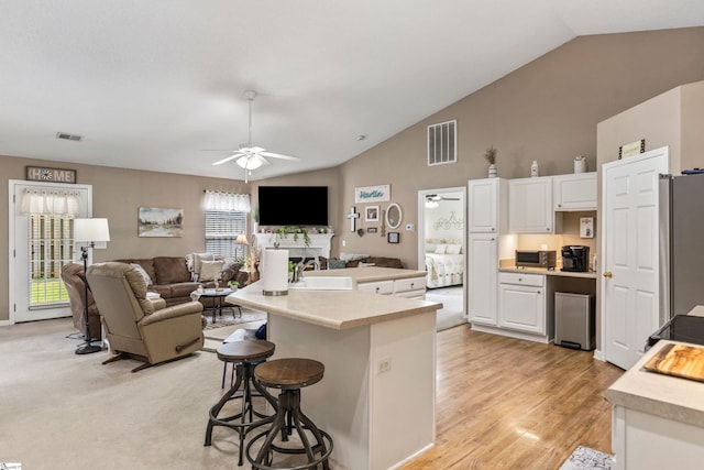 243 Rivers Edge Dr, Easley, SC 29642 - kitchen featuring freestanding refrigerator, ceiling fan, white cabinets, a kitchen bar, and light countertops