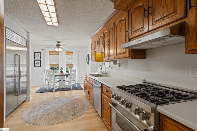 105 Fox Chase Ct, Simpsonville, SC 29680 - kitchen with stainless steel appliances, under cabinet range hood, brown cabinetry, a textured ceiling, and light wood-style floors