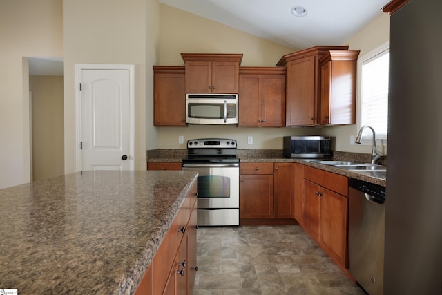18 Herndon Ct, Simpsonville, SC 29681 - kitchen featuring appliances with stainless steel finishes, dark countertops, vaulted ceiling, brown cabinets, and stone finish flooring
